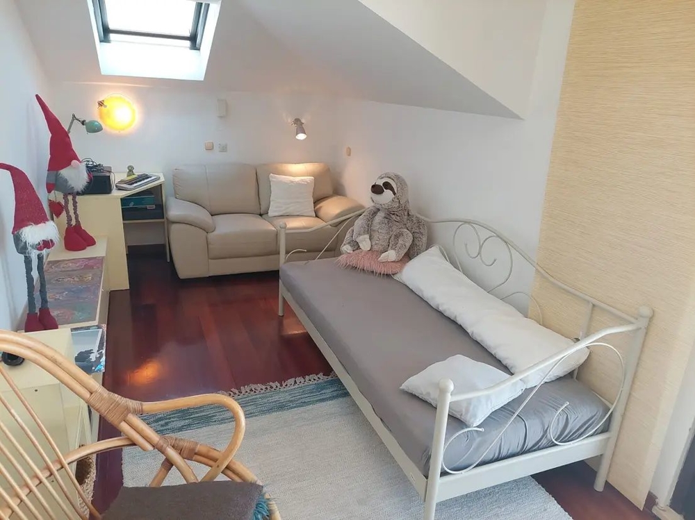 Szoba ággyal, kanapéval, tetőablakkal és dekorációkkal, köztük plüssállatokkal