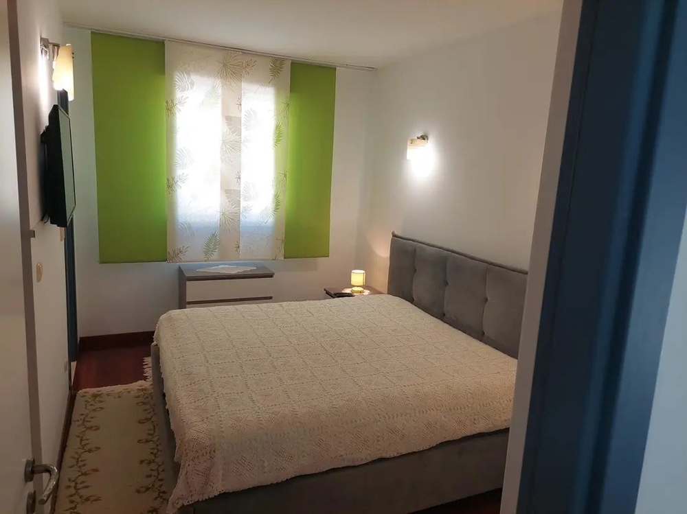 Hálószoba nagy ággyal és zöld függönyökkel