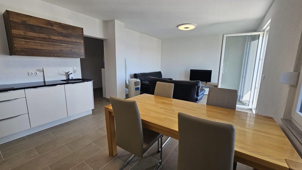 Modern nyitott konyha fa elemekkel, étkezővel és erkélyre nyíló ülősarokkal.