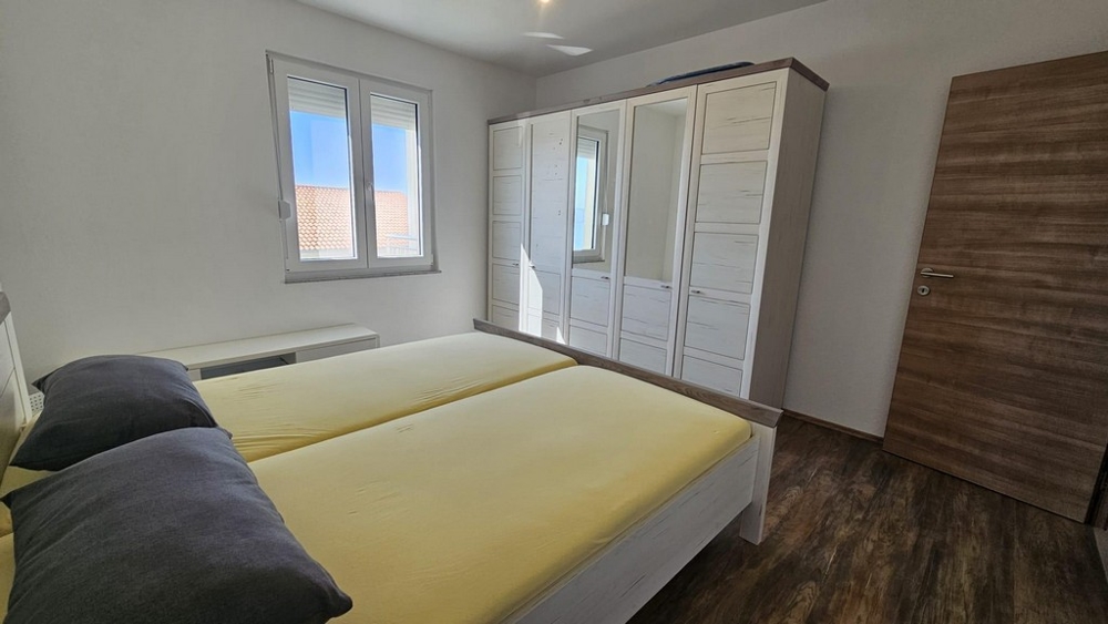 Tágas hálószoba franciaággyal, nagy gardróbbal és tengerre néző kilátással az ablakon keresztül.