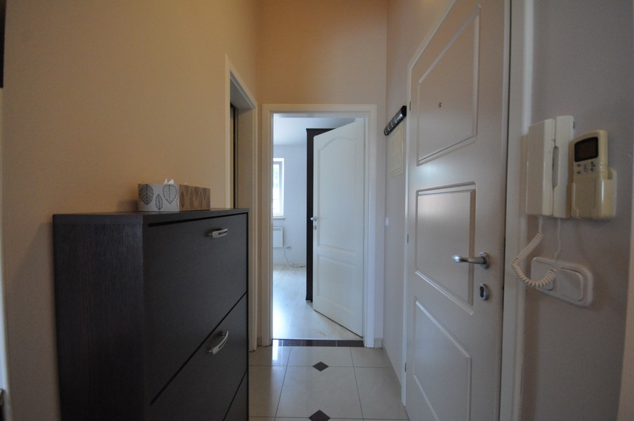 Folyosó fehér ajtóval, sötét szekrény és kaputelefon a falon, hozzáférés a különböző helyiségekhez