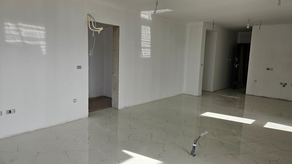 Befejezetlen szoba világos padlólappal, készen áll a további belső munkákra