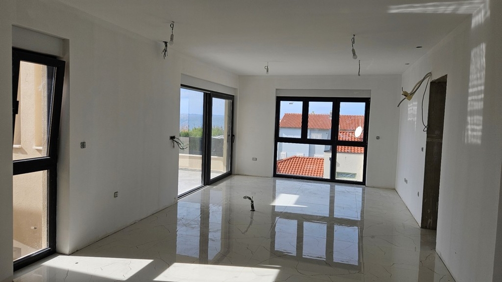 Nappali nagy ablakokkal, kilátással a vörös tetőkre és az erkélyre