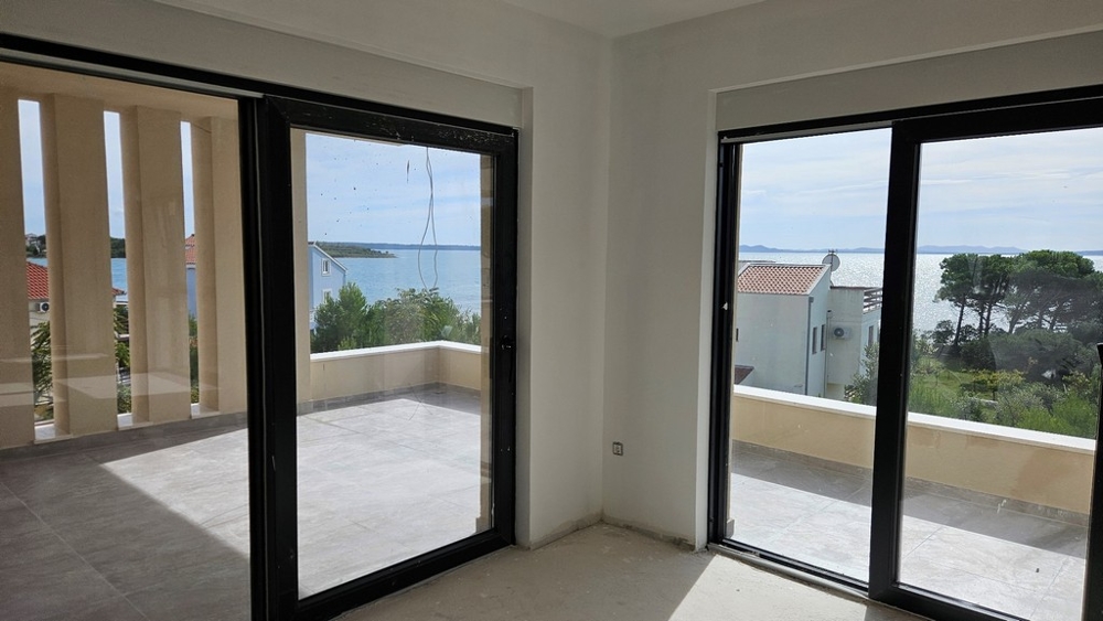 Nappali nagy üvegablakokkal, kilátással a tengerre és erkéllyel