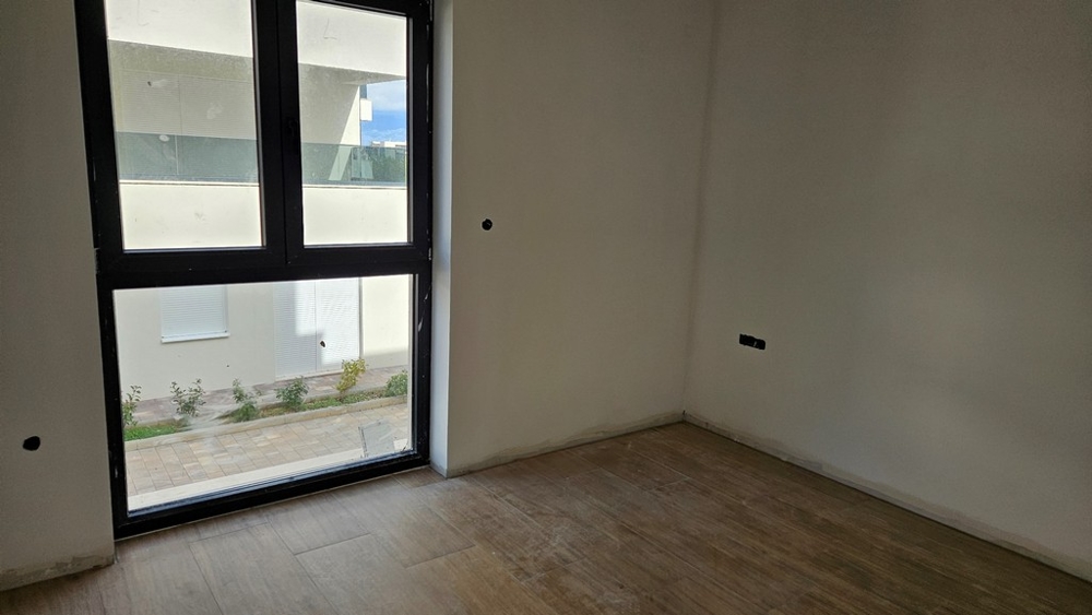 Egy másik szoba nagy ablakokkal, a kilátás egy modern épületet és egy burkolt területet mutat.