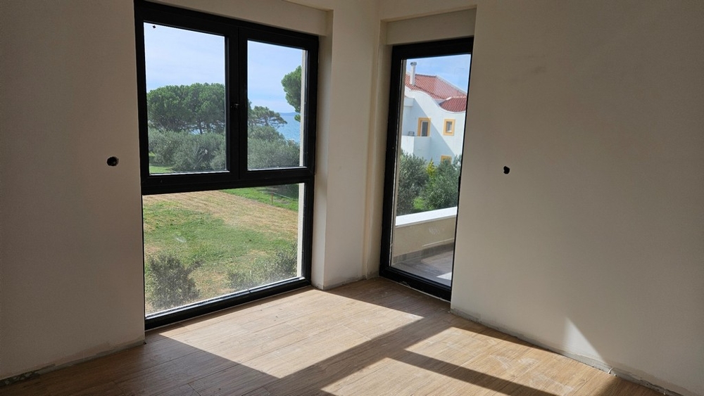 Fénnyel teli tér nagy ablakokkal, ahonnan kilátás nyílik a tengerre és a környező természetre.