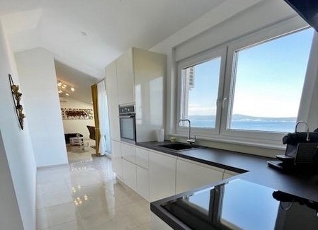 Konyha fehér szekrényekkel, nagy ablakkal és tengerre néző kilátással.