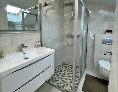 Modern fürdőszoba zuhanykabinnal és mosdóval.