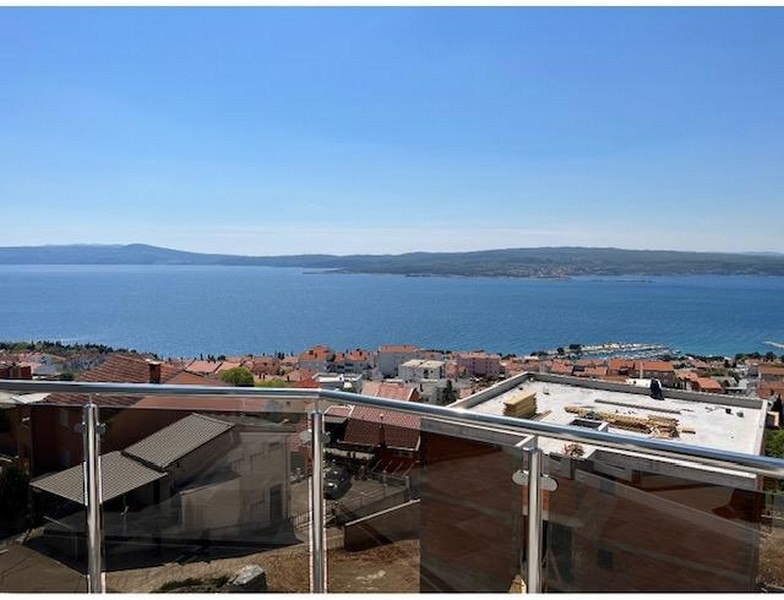 Terasz üvegkorlátokkal, panorámás kilátással a tengerre és a városra.