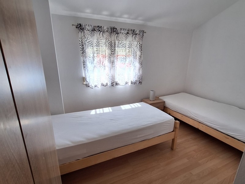 Hálószoba két egyszemélyes ággyal és világos függönyökkel