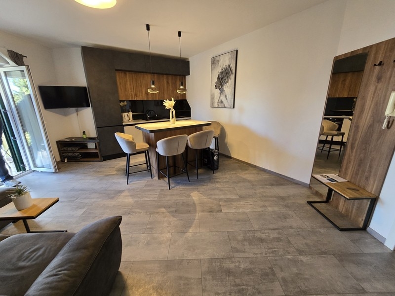 Modern nyitott konyha-nappali étkezővel és stílusos függőlámpákkal egy abbáziai apartmanban.