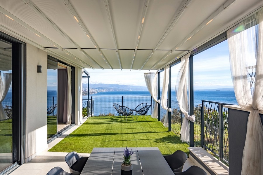 Fedett terasz kerttel és panorámás kilátással a tengerre.