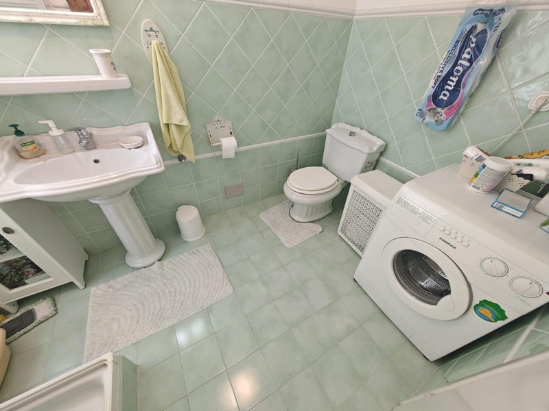 Fürdőszoba mosógéppel és zöld csempével