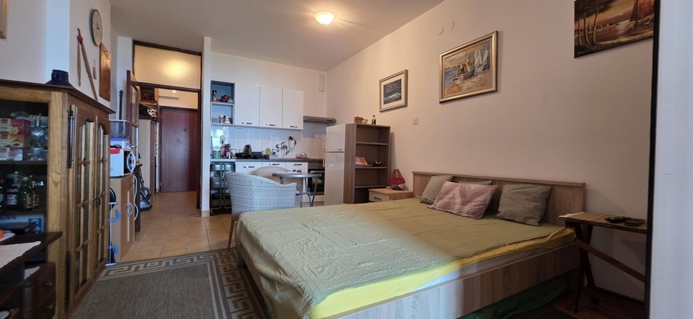 Stúdió ággyal, konyhasarokkal és kijárattal a folyosóra