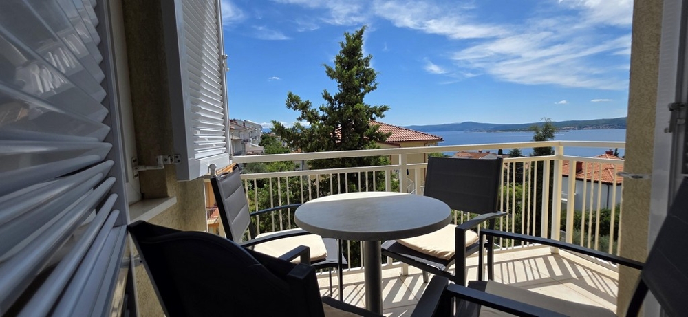 Erkély asztallal, székekkel és kilátással a tengerre