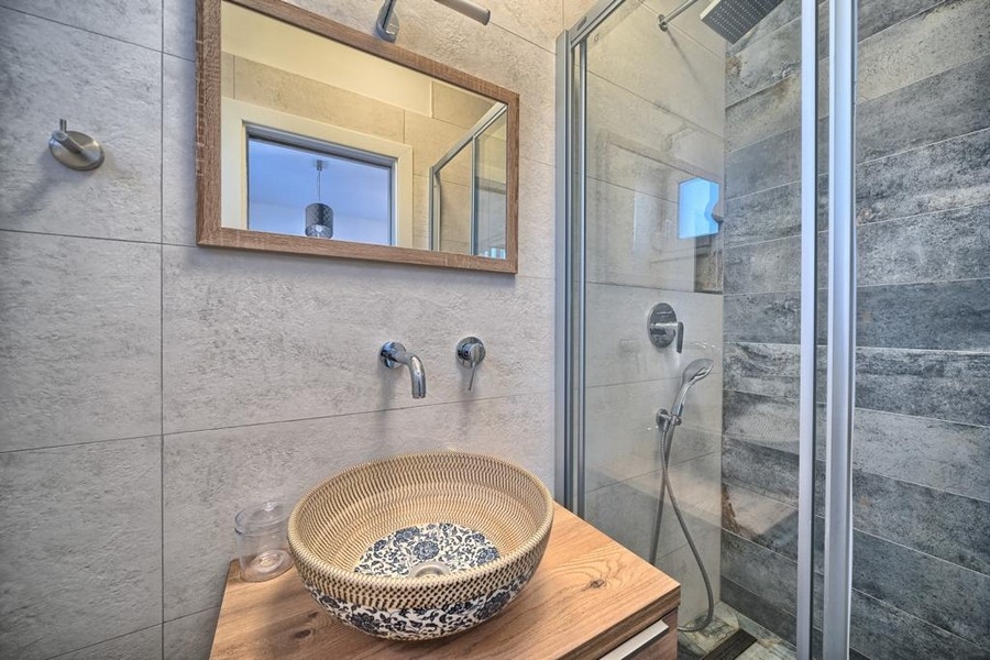 Fürdőszoba mosdóval, tükörrel és zuhanyzóval