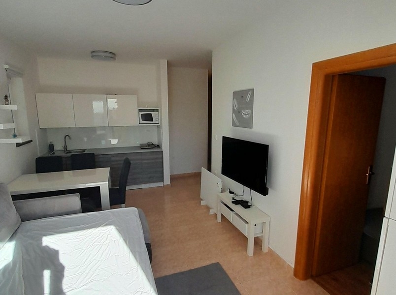 Nappali televízióval, étkezőasztallal és kijárattal a hálószobába