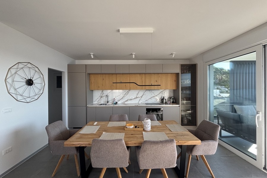 Modern felszerelt konyha étkezővel és nagy ablak előtt