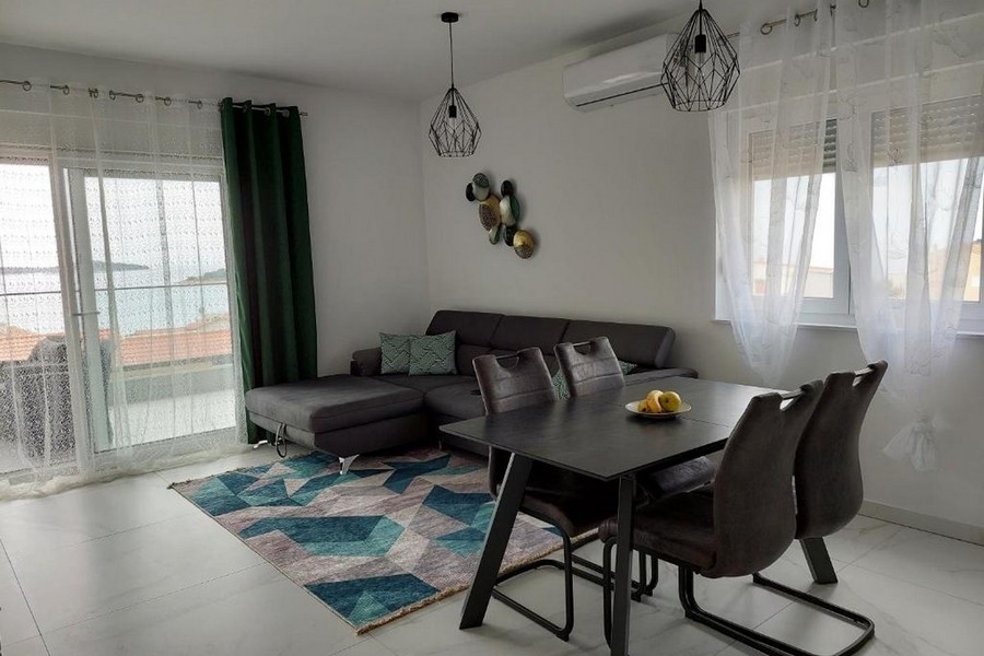 Nappali kanapéval, étkezőasztallal és tengerre néző kilátással a nagy ablakon keresztül