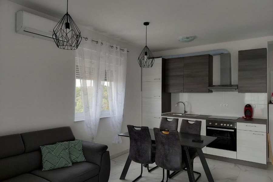 Nyitott nappali és konyha modern felszerelt konyhával és étkezőasztallal