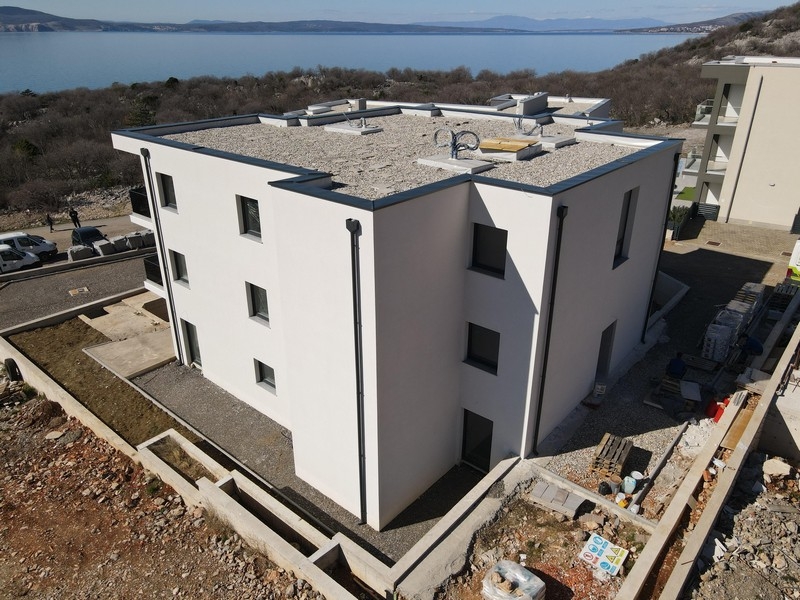 Új bérház lapos tetővel és modern építészettel a part közelében