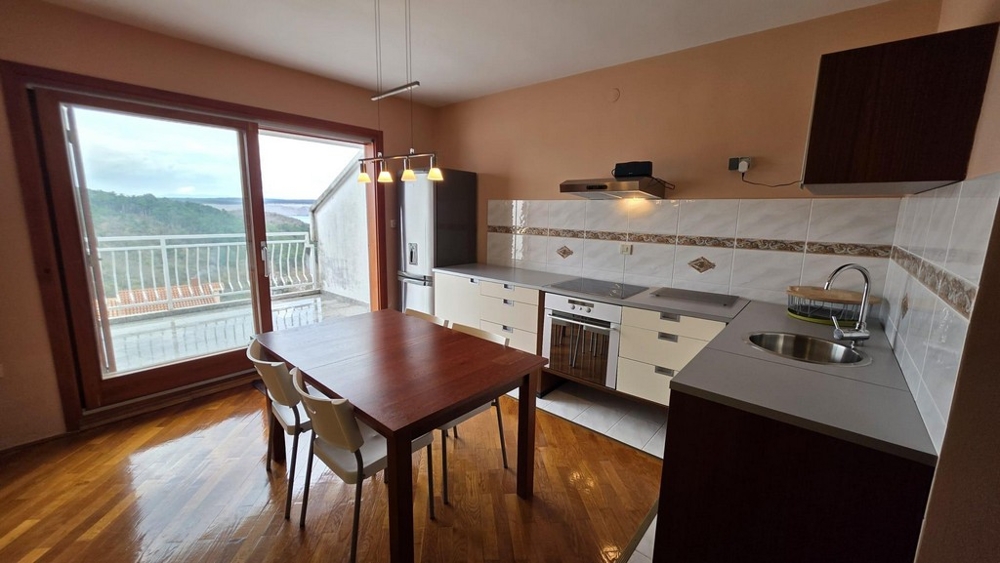 Nappali beépített konyhasarokkal és kilátással a teraszra.