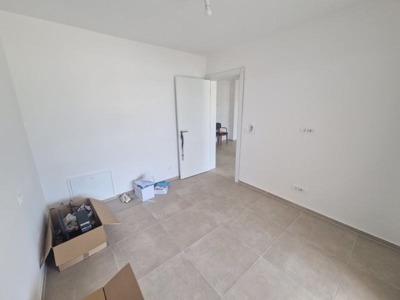 Szoba járólapozott padlóval és semleges bútorokkal