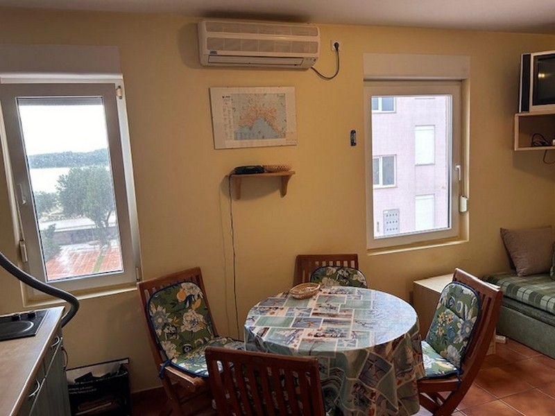 Nappali és étkezősarok kerek asztalcsoporttal és tengerre néző kilátással az ablakon keresztül