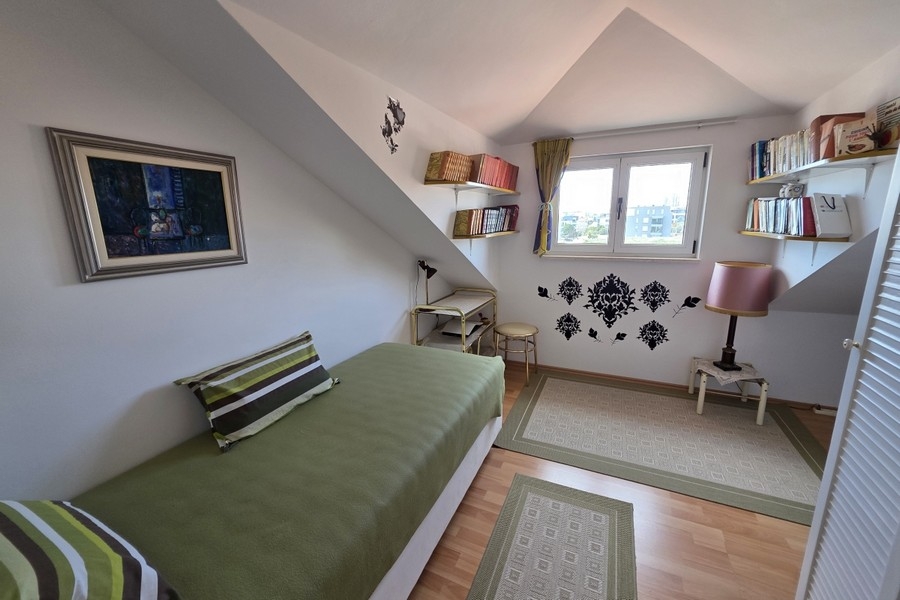 Világos tetőtéri hálószoba egyszemélyes ággyal, dolgozósarokkal és ferde mennyezettel