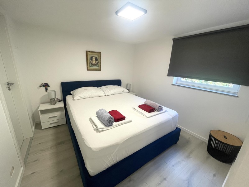 Hálószoba franciaággyal a földszinti apartmanban Njivice városában