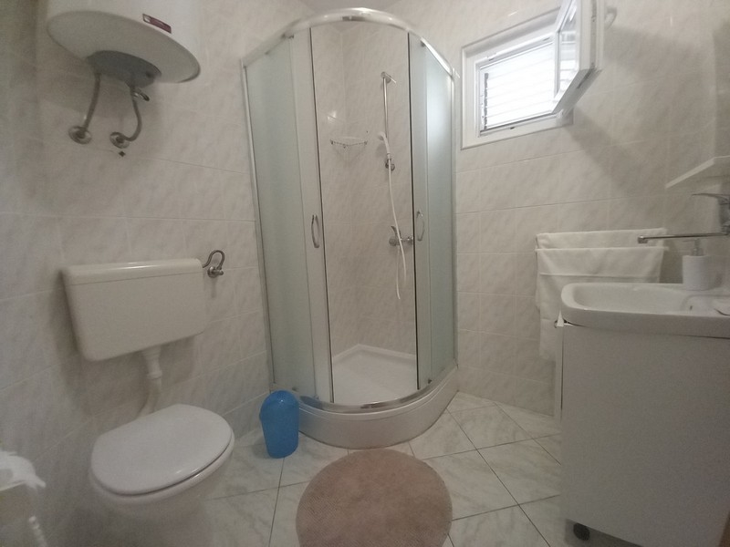 Világos fürdőszoba WC-vel és zuhanyzóval.