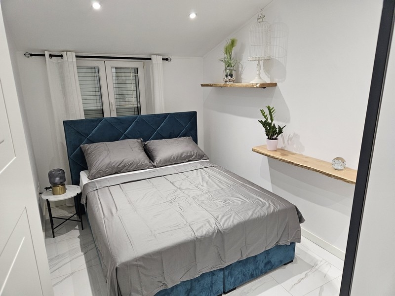 Hangulatos hálószoba kék fejtámlával és dísznövényekkel egy horvátországi ingatlanban