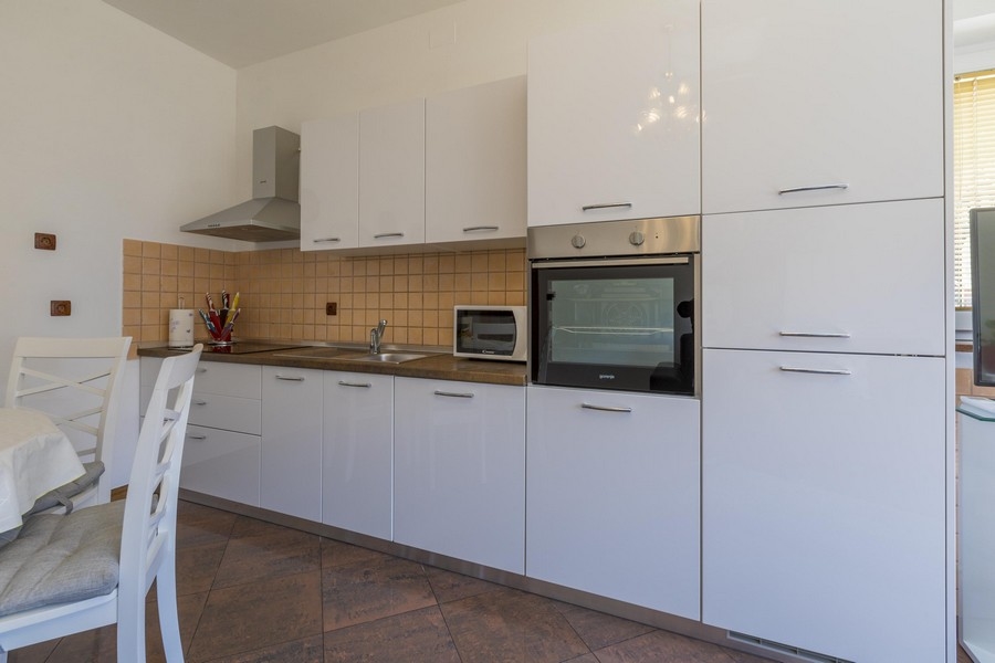 Modern fehér konyha étkezővel egy tengerparti ingatlanban Horvátországban