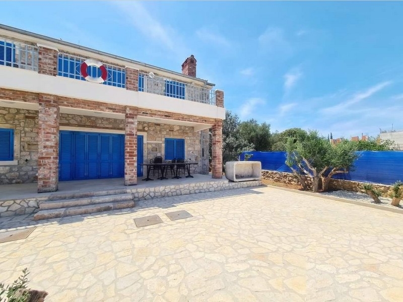 Horvátországban eladó egy hangulatos kőház elölnézete szabadtéri étkezővel.