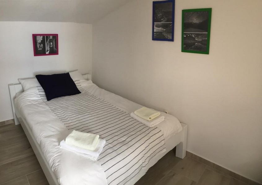 Egy másik hálószoba a kőházban franciaággyal, egyszerű bútorokkal és művészettel a falakon