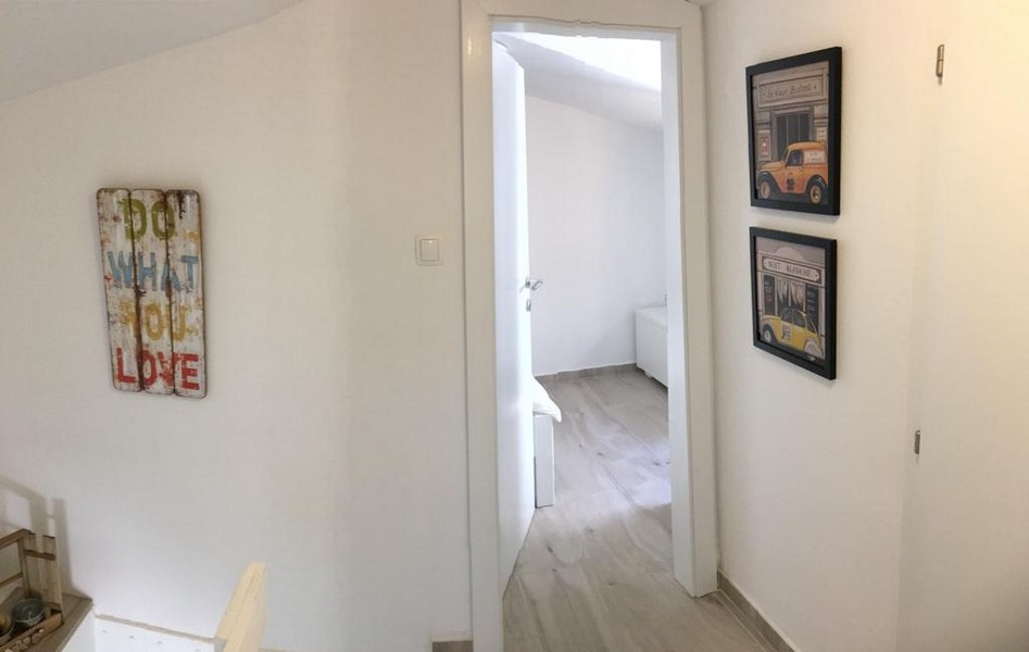 A kőház egyszerű folyosója fehér ajtóval és minimalista dekorációval további helyiségekbe vezet