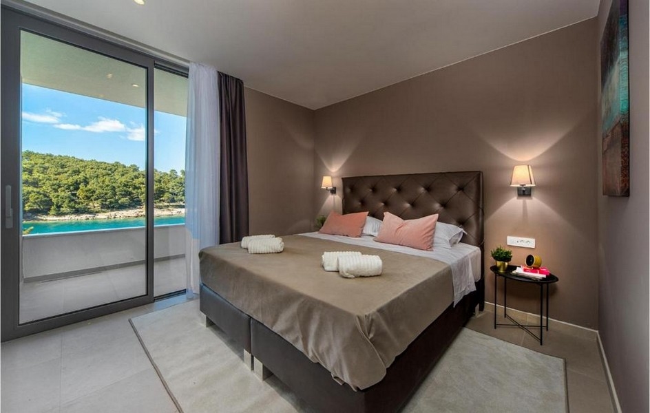 Hálószoba franciaággyal, modern dizájnnal és tengerre néző kilátással a braci villában.