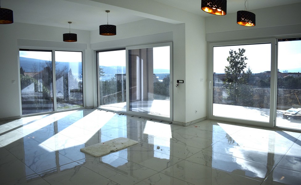 Világos, napsütötte nappali egy villában Krk szigetén, nagy ablakokkal és kilátással a tengerre.