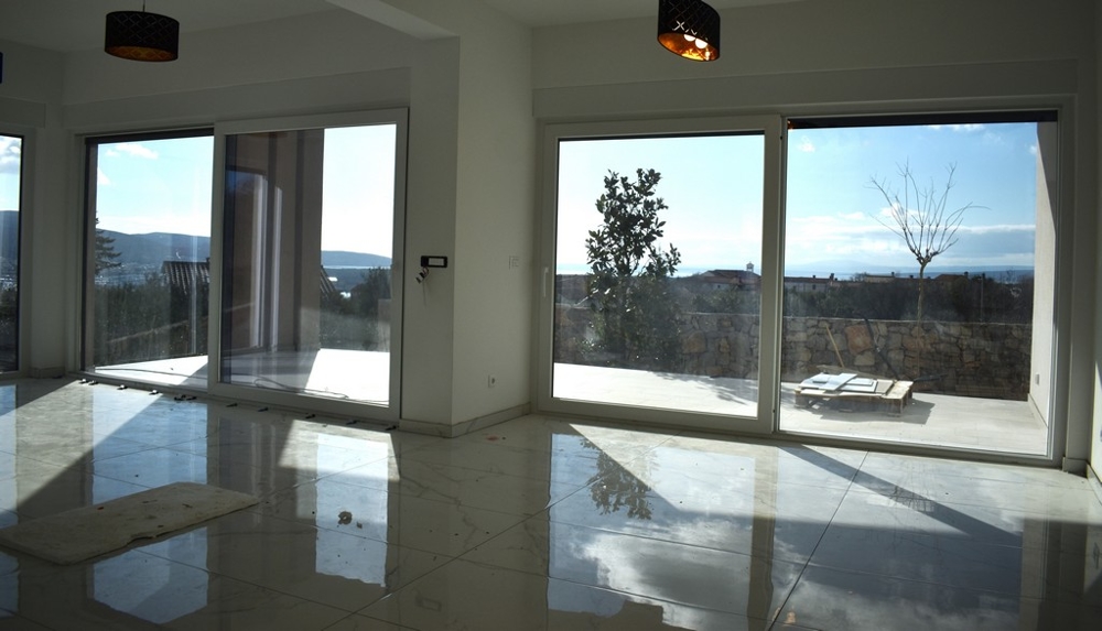 Tágas, üres nappali fehér falakkal és nagy ablakkal egy villában Krk-n.