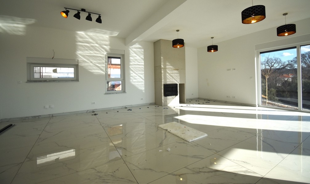 Napfényes nappali kandallóval és ablakfronttal egy modern villában Krk szigetén.