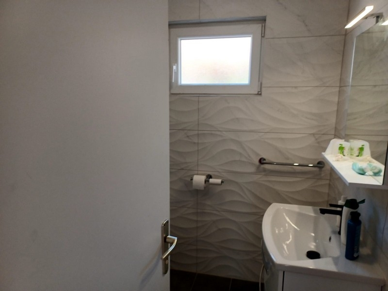 A horvátországi Cres szigeten lévő villában modern hullámos csempével és fehér mosdóval felszerelt fürdőszoba eladó.