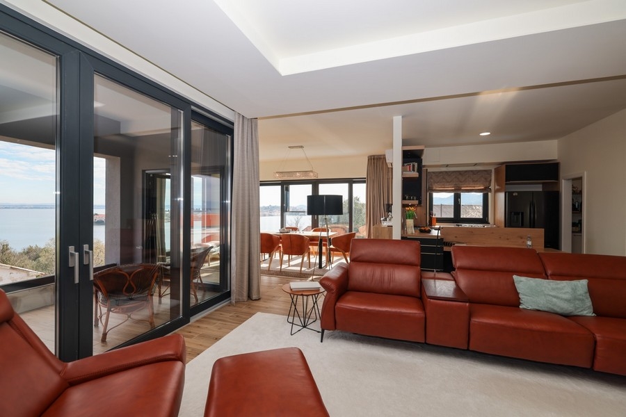 Ugljani villában eladó nappali L alakú bőrkanapéval és nyitott konyhával.