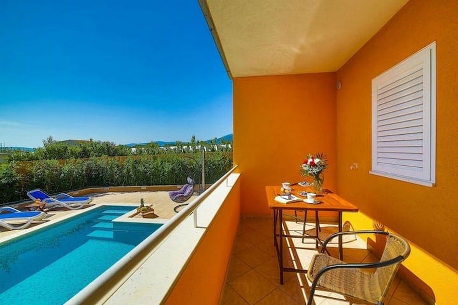 Erkélyes kilátás a horvátországi Kaštel Lukšić apartmanház medencéjére, asztallal és székekkel