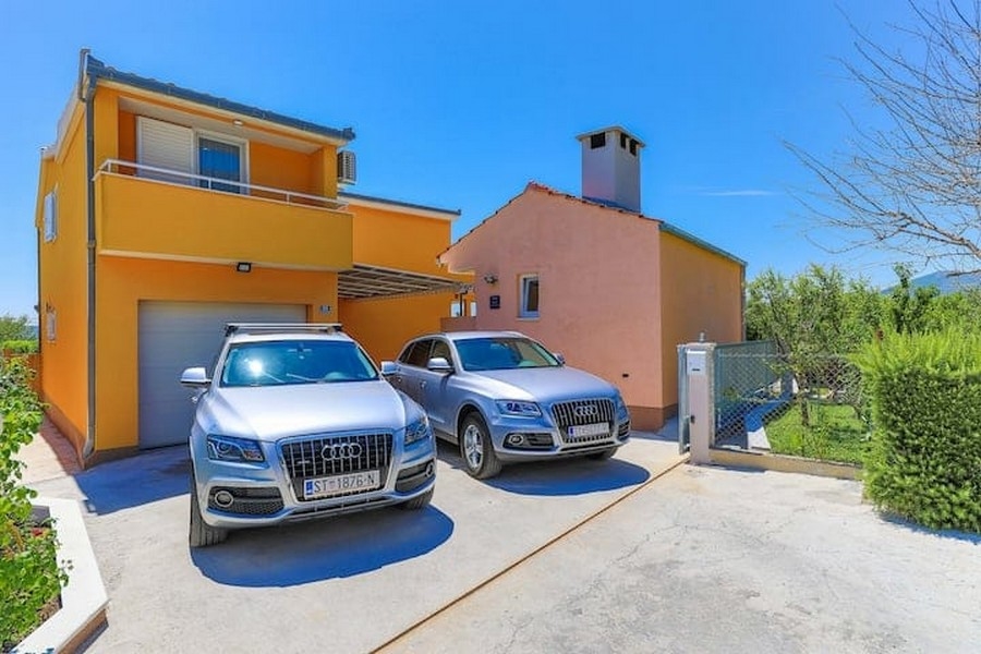 A horvátországi Kaštel Lukšić lakóház első bejárata két parkoló autóval