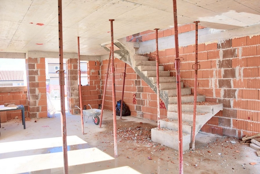 Az épülő ikerház belső képe beton lépcsőkkel és téglafalakkal