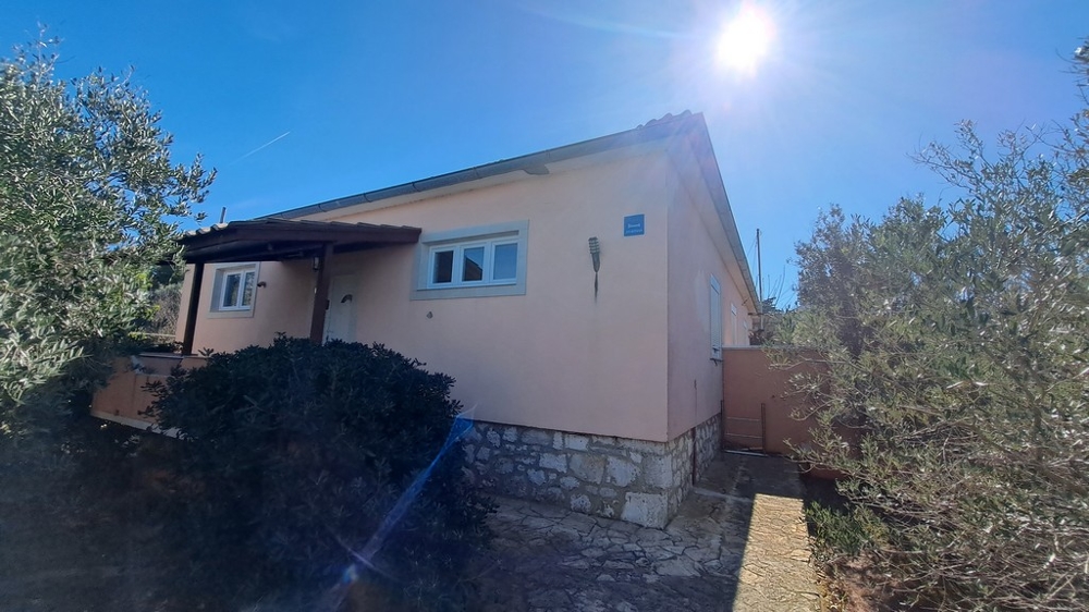 Kilátás egy mediterrán növényekkel körülvett ház oldaláról, tengerparti ingatlan Horvátországban