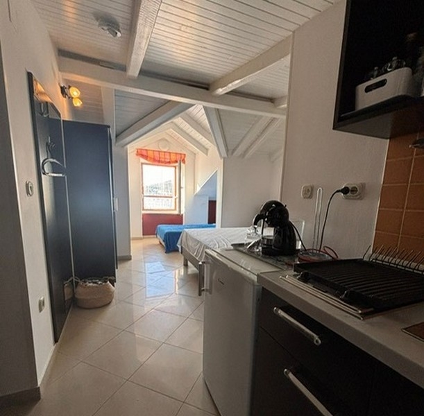 Kompakt konyhasarok szomszédos hálórésszel egy horvát ingatlanban. 4 étkezőasztal, kilátással a kikötőre egy horvátországi ingatlan ablakán keresztül