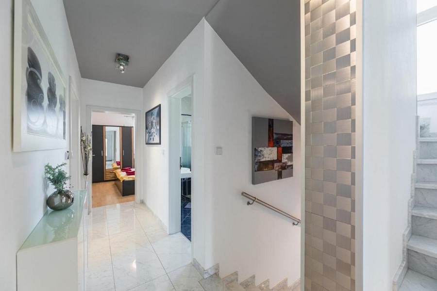 Egy horvátországi bérház bejárata és folyosója tengerre néző kilátással, fényes padlólapokkal, lépcsőházzal és faldíszekkel