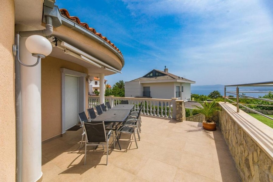 Horvátországi bérház nagy terasza, hosszú asztallal és székekkel, kilátással a tengerre