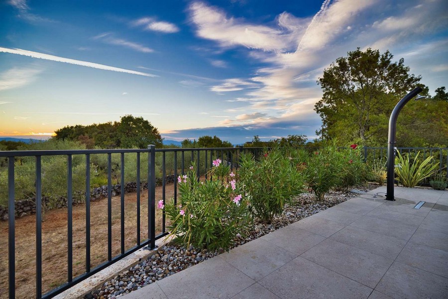 Az ingatlan gondozott kertje és természeti környezete Krk szigetén, tengerre néző kilátással a távolban